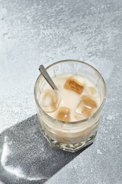 Beyaz Rus kokteyli kahve likörü ve votkadan yapılan bir kokteyl. Kaşık kaplı kokteyl bardağı, güneş ışığı ve uzun gölgeli eski bir masa. Klasik güçlü kokteyl koleksiyonu.