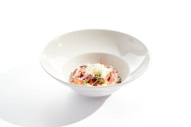 Beyaz restoran tabağında risotto alla carbonara. Pastırmalı ve yumurtalı risotto, mikro yeşilliklerle süslenmiş. Parmesan peynirli risotto.
