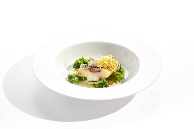 Brokoli ve krema soslu kızarmış balık. Yeşil yapraklı sağlıklı kızarmış morina balığı. Kızarmış balık beyaz arka planda izole edilmiş.