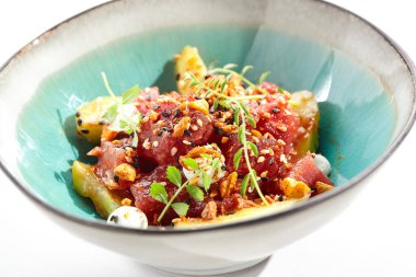 Ton balığı ve salatalık kasesi. Mavi salata kasesi beyaz arka planda izole edilmiş. Mikro yeşillik ve susam ile süslenmiş salata, doğranmış ton balığı, dilimlenmiş salatalık ve maydanoz yeşil yaprak. Baharatlı soslu çiğ ton balığı.