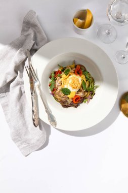 Yabanturpu soslu sığır dili salatası sosu ve taze yeşil yapraklar. Cam kaplı beyaz masa üzerinde gümüş çatal bıçak takımı olan beyaz bir restoran tabağı. Sebzeli et kasesi. Salata lokantası