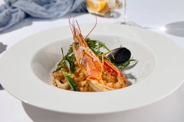 Beyaz arka planda çağdaş tarzda deniz mahsullü risotto. İtalyan pilavı, karides, midye, frutti di mare tarzı kalamar. Deniz ürünleri ve pirinçle yaz yemeği. Yaz günü deniz ürünleri konsepti