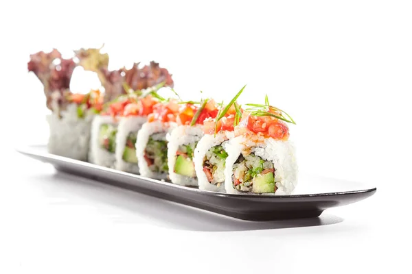 Healthy vegetarian Japanese lunch. Vegan sushi roll with avocado and mushrooms inside. Topped with tomato. Vegetarian sushi rolls dish. Restaurant asian vegan food isolated on white background