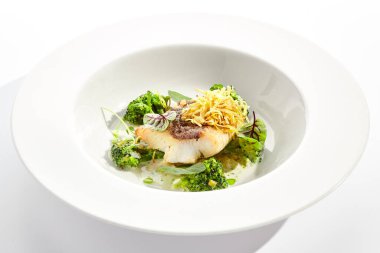 Brokoli ve krema soslu kızarmış balık. Yeşil yapraklı sağlıklı kızarmış morina balığı. Kızarmış balık beyaz arka planda izole edilmiş.