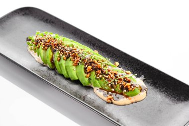 Beyaz arka planda avokado carpaccio yeşil salatası. Sağlıklı organik vejetaryen yemeği. Ketogenik diyet. Unagi soslu ve fıstıklı avokado dilimleri. Restoran menüsünde trend yemeği