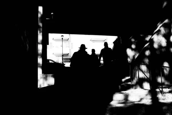 三个人穿行在地下通道上的富有创意的高层黑白人物形象 — 图库照片