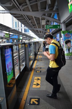 Traveller waits for BTS Skytrain  in Bangkok Thailand clipart