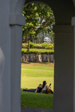 Singapur - 30 Ekim 2025: Fort Canning Park 'taki çimenlikte insanlar dinleniyor. Fort Canning Hill, Singapur 'un tarihine bir geçiş kapısı, kutlamalar için bir mekan ve dokuz tarihi bahçesi var.