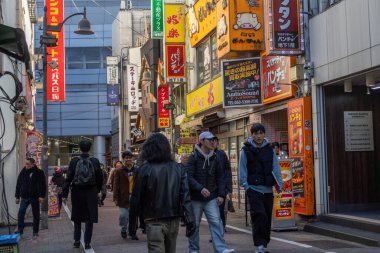 Tokyo, Japonya - 16 Aralık 2025: İnsanlar Tokyo 'nun enerjisinin gerçekten canlandığı Shibuya Center-Gai' yi ziyaret ediyor. Neon ışıkları, modaya uygun dükkanlar, atari salonları ve sonsuz yiyecek seçenekleriyle doluydu.