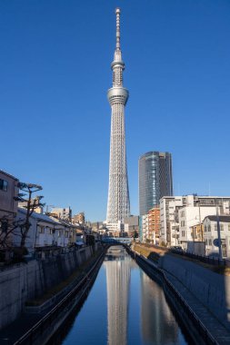 Tokyo, Japonya - 17 Aralık 2025: Tokyo Skytree 'nin inanılmaz yapısı tersine döndü ve nehre yansıdı. Gökyüzü ağacı 634 metre yüksekte süzülüyor ve Tokyo 'nun inanılmaz panoramik manzarasını veriyor.