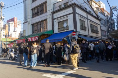 Tokyo, Japonya-28 Aralık 2025: Tokyo 'daki Tsukiji Dış Pazarı' nı ziyaret eden turistler. Pazar, özellikle deniz ürünleri aşıkları olmak üzere aşçılık deneyimleri arayan ziyaretçiler için hareketli bir merkez olmaya devam ediyor.
