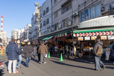 Tokyo, Japonya-28 Aralık 2025: Tokyo 'daki Tsukiji Dış Pazarı' nı ziyaret eden turistler. Pazar, özellikle deniz ürünleri aşıkları olmak üzere aşçılık deneyimleri arayan ziyaretçiler için hareketli bir merkez olmaya devam ediyor.