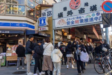 Tokyo, Japonya-28 Aralık 2025: Tokyo 'daki Tsukiji Dış Pazarı' nı ziyaret eden turistler. Pazar, özellikle deniz ürünleri aşıkları olmak üzere aşçılık deneyimleri arayan ziyaretçiler için hareketli bir merkez olmaya devam ediyor.