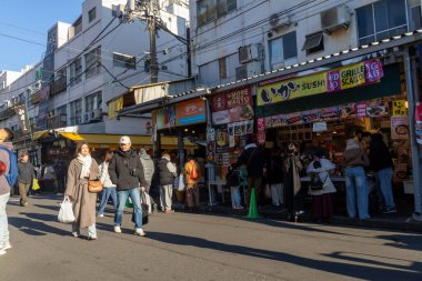 Tokyo, Japonya-28 Aralık 2025: Tokyo 'daki Tsukiji Dış Pazarı' nı ziyaret eden turistler. Pazar, özellikle deniz ürünleri aşıkları olmak üzere aşçılık deneyimleri arayan ziyaretçiler için hareketli bir merkez olmaya devam ediyor.