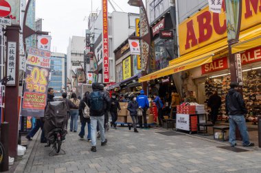 Tokyo, Japonya - 27 Aralık 2025: Tokyo, Japonya 'da Ueno Ameyoko canlı pazar sahnesi. Yükseltilmiş demiryolu hattının altında bir mağaza koleksiyonu.