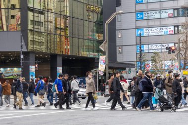 Tokyo, Japonya - 27 Aralık 2025: Tokyo, Akihabara 'da kalabalık caddeyi geçen büyük bir kalabalık. Akihabara, Japon anime, oyun ve elektronik kültürünün küresel merkezi olarak bilinir.