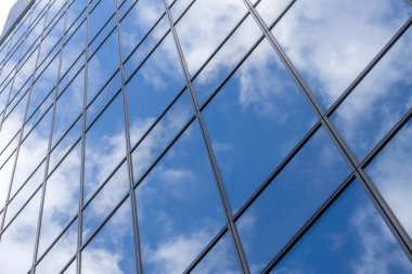 Mavi gökyüzü ve bulut yüksek binadaki cam pencereye yansıyor. Mavi gökyüzünü ve bulutu yansıtan modern cam gökdelen.