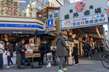 Tokyo, Japonya-28 Aralık 2025: Tokyo 'daki Tsukiji Dış Pazarı' nı ziyaret eden turistler. Pazar, özellikle deniz ürünleri aşıkları olmak üzere aşçılık deneyimleri arayan ziyaretçiler için hareketli bir merkez olmaya devam ediyor.