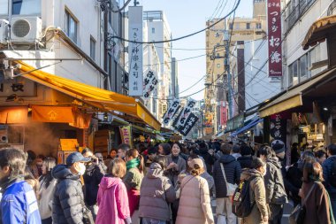 Tokyo, Japonya-28 Aralık 2025: Tokyo 'daki Tsukiji Dış Pazarı' nı ziyaret eden turistler. Pazar, özellikle deniz ürünleri aşıkları olmak üzere aşçılık deneyimleri arayan ziyaretçiler için hareketli bir merkez olmaya devam ediyor.