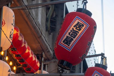 Tokyo, Japonya - 17 Aralık 2025: Izakaya dilinde Japonca Kanji yazısıyla kırmızı fener. Izakaya, alkollü içecekler ve çok çeşitli küçük, paylaşılabilir yemekler sunan sıradan bir Japon barı veya tavernasıdır.