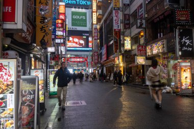 Tokyo, Japonya - 24 Aralık 2025: Shinjuku, Tokyo 'da renkli iş afişleri ve neon levhaları asılmış sokak. Shinjuku genellikle hareketli gece hayatı nedeniyle Uykusuz Kasaba olarak adlandırılır.