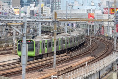 Tokyo, Japonya - 27 Aralık 2025 Tokyo metrosu Tokyo 'daki Ueno Ameyoko canlı pazarından geçiyor. Trenler, aşağıdaki alışveriş caddesi ve şehrin ufuk çizgisiyle viyadük üzerinde çalışıyor.