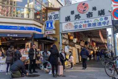 Tokyo, Japonya-28 Aralık 2025: Tokyo 'daki Tsukiji Dış Pazarı' nı ziyaret eden turistler. Pazar, özellikle deniz ürünleri aşıkları olmak üzere aşçılık deneyimleri arayan ziyaretçiler için hareketli bir merkez olmaya devam ediyor.