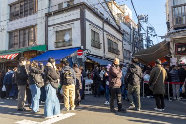Tokyo, Japonya-28 Aralık 2025: Tokyo 'daki Tsukiji Dış Pazarı' nı ziyaret eden turistler. Pazar, özellikle deniz ürünleri aşıkları olmak üzere aşçılık deneyimleri arayan ziyaretçiler için hareketli bir merkez olmaya devam ediyor.