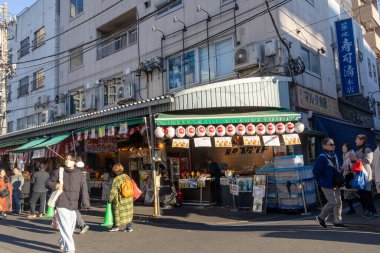Tokyo, Japonya-28 Aralık 2025: Tokyo 'daki Tsukiji Dış Pazarı' nı ziyaret eden turistler. Pazar, özellikle deniz ürünleri aşıkları olmak üzere aşçılık deneyimleri arayan ziyaretçiler için hareketli bir merkez olmaya devam ediyor.
