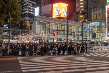 Tokyo, Japonya - 16 Aralık 2025: İnsanlar Tokyo 'daki Shibuya Scramble Geçidini geçmek için trafik ışığının yeşile dönmesini bekliyor.