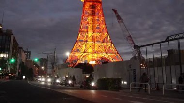 Tokyo, Japonya- 22 Aralık 2025: Tokyo Kulesi sıcak turuncu renkle aydınlanıyor. Dik durarak, şehir manzaralarını süpürüyor, özellikle de karanlık çöktüğünde, Tokyo 'yu sıcak ve büyüleyici bir şekilde aydınlatıyor.