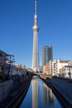 Tokyo, Japonya - 17 Aralık 2025: Tokyo Skytree 'nin inanılmaz yapısı tersine döndü ve nehre yansıdı. Gökyüzü ağacı 634 metre yüksekte süzülüyor ve Tokyo 'nun inanılmaz panoramik manzarasını veriyor.