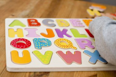 Bebek erken öğreniyor. Alfabenin tahta harfleri. Çocuklar bulmaca okuyor. Çocukların eğitimsel oyunu, doğru yere uyuyor. Öğretmenlik entellektüel çocuk oyun tahtası geliştirme.
