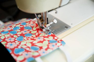 Coronavirus teması. Evde koruyucu maskeler yapmak. Dikiş makinesi ve bez parçaları üretim aşamasında. DIY Ev yapımı Covid-19 'a karşı pandemik koruma için.