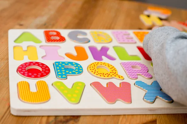 Baby early learning. Wooden letters of the alphabet. Children reading puzzle. Kids educational game, match the right place. Teaching develop intellectual kid game board.