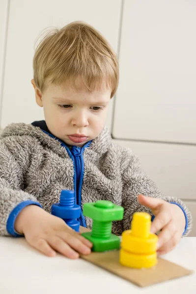 Shapes, colors and fine motor skills. toddler turns the nut on the bolt. Task to twist correct color part on matching thread.