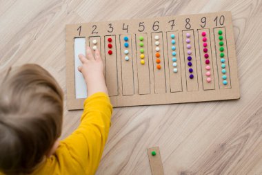 Pamuk yumaklarıyla kayışları numaralandırılmış oyuğa yerleştirin. Anaokulları için okul öncesi eğitim yardımı. Çocuklar erken yaşta zeka için montessori setini öğreniyorlar