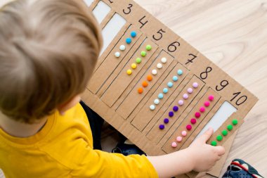 Pamuk yumaklarıyla kayışları numaralandırılmış oyuğa yerleştirin. Anaokulları için okul öncesi eğitim yardımı. Çocuklar erken yaşta zeka için montessori setini öğreniyorlar