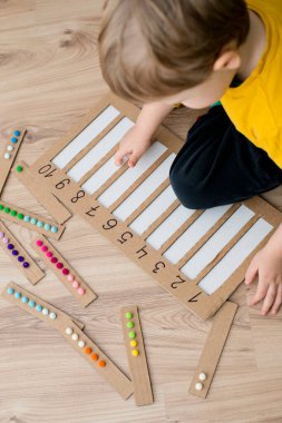 Pamuk yumaklarıyla kayışları numaralandırılmış oyuğa yerleştirin. Anaokulları için okul öncesi eğitim yardımı. Çocuklar erken yaşta zeka için montessori setini öğreniyorlar