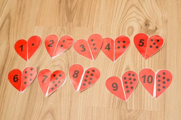 counting hearth shape game. dots and numbers. find a pair. wood background. kid playing on the floor. mathematic task.