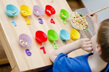 Küçük çocuk basit matematik egzersizleri yapıyor. Erken eğitim, sayma oyunu. Çocuklar için okul öncesi egzersizi. 1 'den 10' a sıralama.