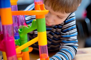 Hadi misket yarışı oynayalım. Çocuğun duygusal bir yüzü var. Evde çocukluk aktiviteleri. Anaokulu çocuğu top parkuruyla oynuyor.