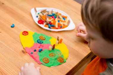 Paskalya konsepti. Çocuk renkli erişteleri yumurta şeklindeki plastiğin üzerine yerleştiriyor. Çocuklar ev fikirleri için oyuncak, çocuk istihdam, iyi motor beceriler, ergoterapi, duyusal terapi