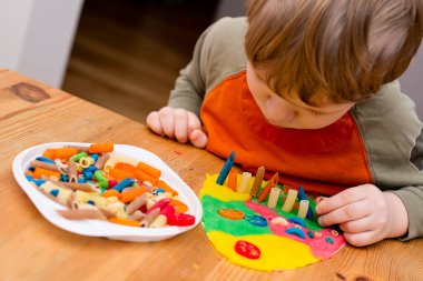 Paskalya konsepti. Çocuk renkli erişteleri yumurta şeklindeki plastiğin üzerine yerleştiriyor. Çocuklar ev fikirleri için oyuncak, çocuk istihdam, iyi motor beceriler, ergoterapi, duyusal terapi