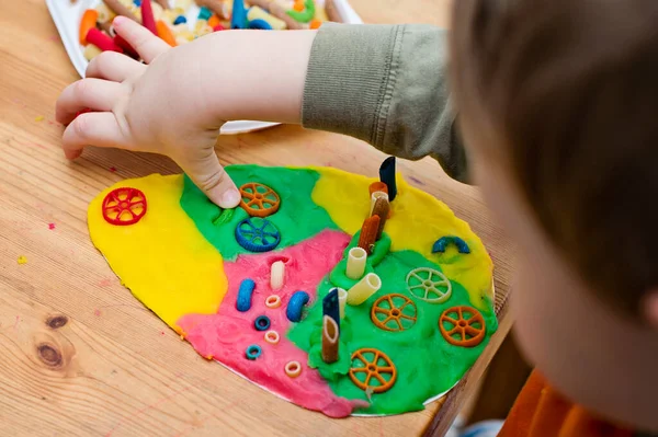 Paskalya konsepti. Çocuk renkli erişteleri yumurta şeklindeki plastiğin üzerine yerleştiriyor. Çocuklar ev fikirleri için oyuncak, çocuk istihdam, iyi motor beceriler, ergoterapi, duyusal terapi