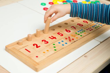 Çocuk farklı renkte ahşap halkalarla oynuyor. Sıralama, iyi motor beceriler, eğitim ve beyin egzersizi için terapi görevi. Matematik oyunu da dahil. Montessori tipi uygulama. Tahta oyuncaklar.