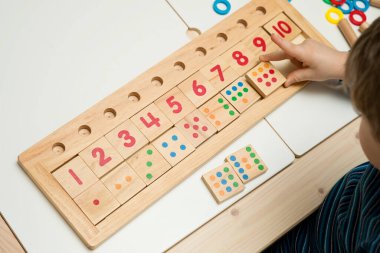 Çocuk farklı renkte ahşap halkalarla oynuyor. Sıralama, iyi motor beceriler, eğitim ve beyin egzersizi için terapi görevi. Matematik oyunu da dahil. Montessori tipi uygulama. Tahta oyuncaklar.