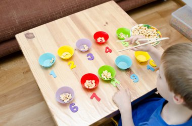 Küçük çocuk basit matematik egzersizleri yapıyor. Erken eğitim, sayma oyunu. Çocuklar için okul öncesi egzersizi. 1 'den 10' a kadar. Montessori matematik aracı. 