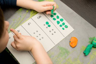 Küçük çocuk basit matematik egzersizleri yapıyor. Erken eğitim, sayma oyunu. Çocuklar için okul öncesi egzersizi. Çocuk ona kadar saymayı öğreniyor. Montessori matematik aracı. 