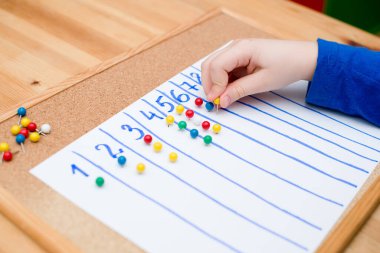 Küçük çocuk basit matematik egzersizleri yapıyor. Erken eğitim, sayma oyunu. Çocuklar için okul öncesi egzersizi. Çocuk ona kadar saymayı öğreniyor. Montessori matematik aracı. 